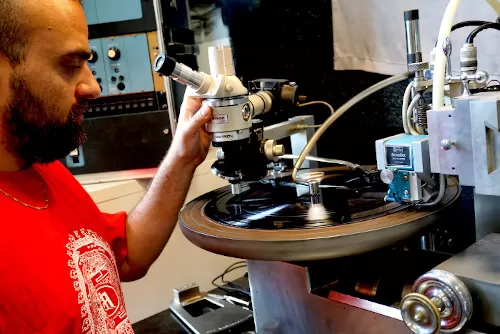 An image of Hari Kishore from Kommunal Dubplate Service inspecting a lacquer disc he's cutting.