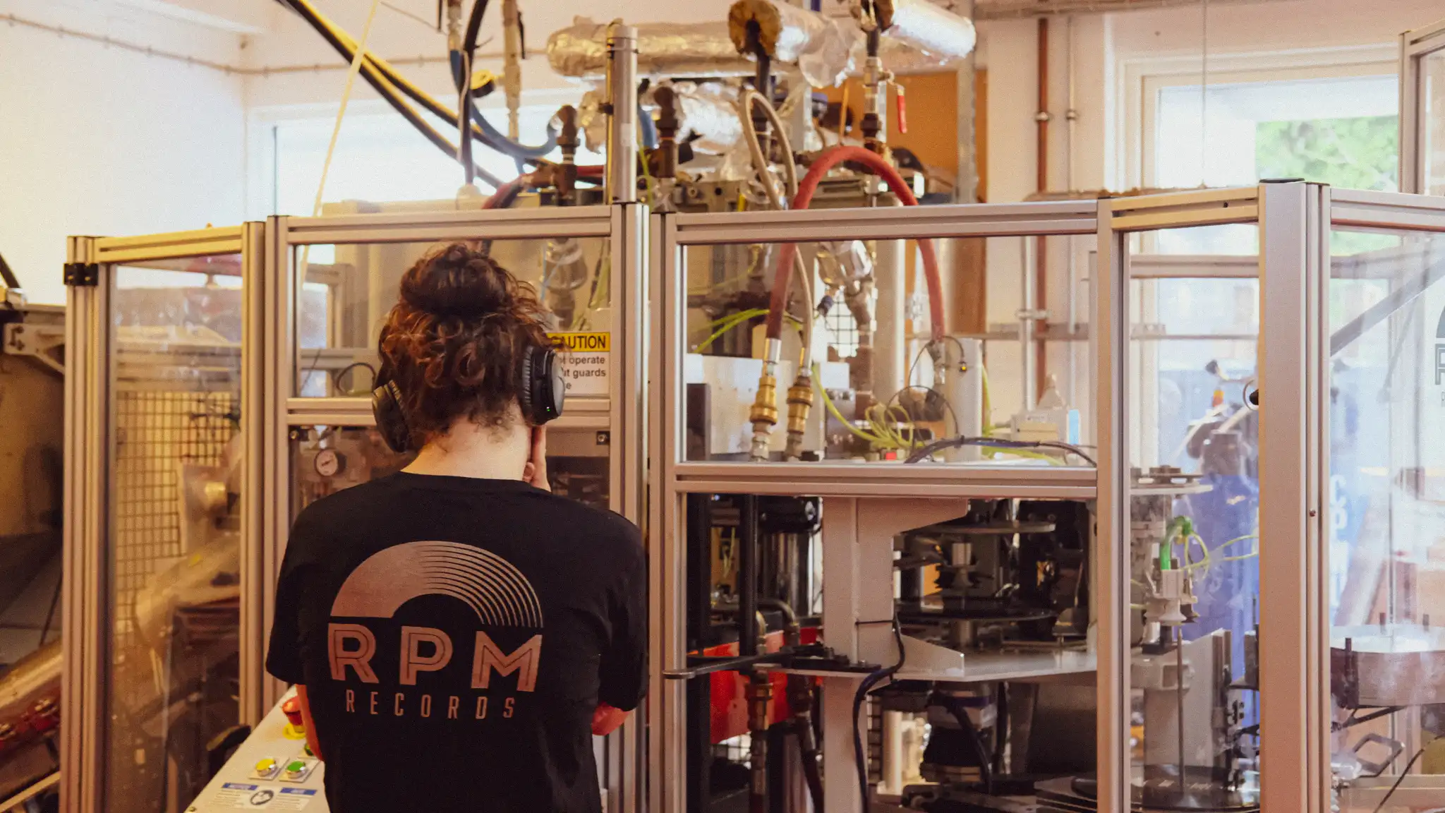 Mathias, chief operating officer, standing in front of Maple, RPM Records' record pressing machine.