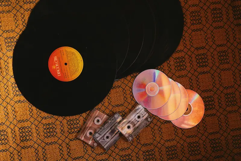 Image of records, cds, and cassettes on an orange rug.